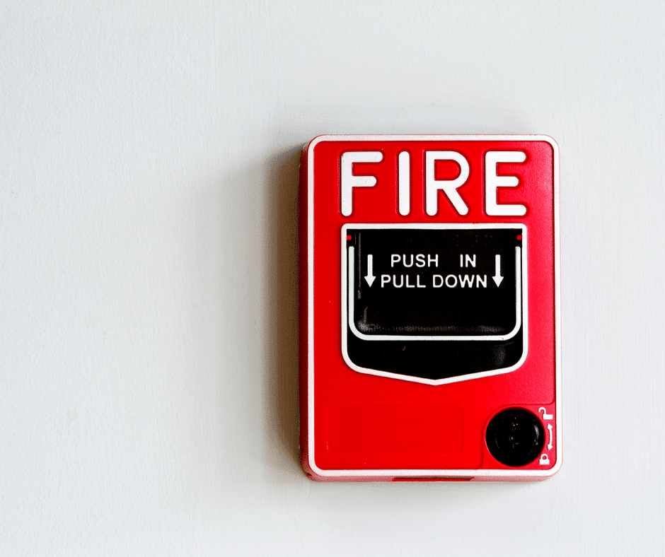 A red fire alarm on a white wall.