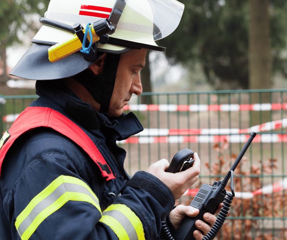 A firefighter wearing a helmet and using a radio, aided by DAS system and ERRCS.