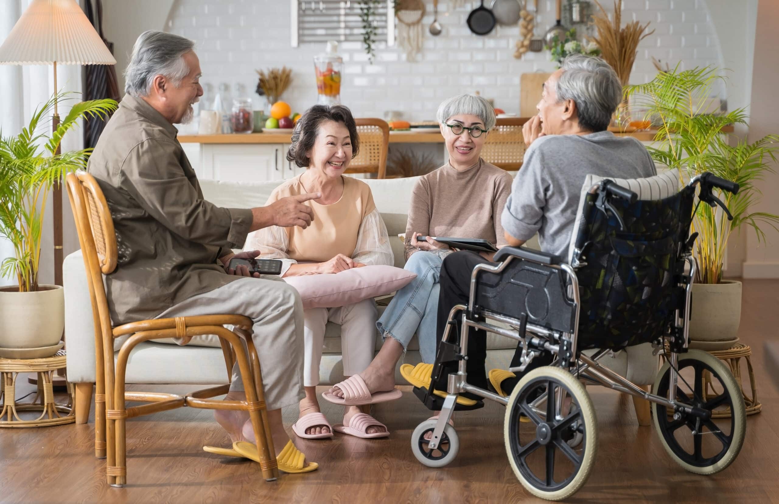 A group of elderly people sitting in a living room with a wheelchair.