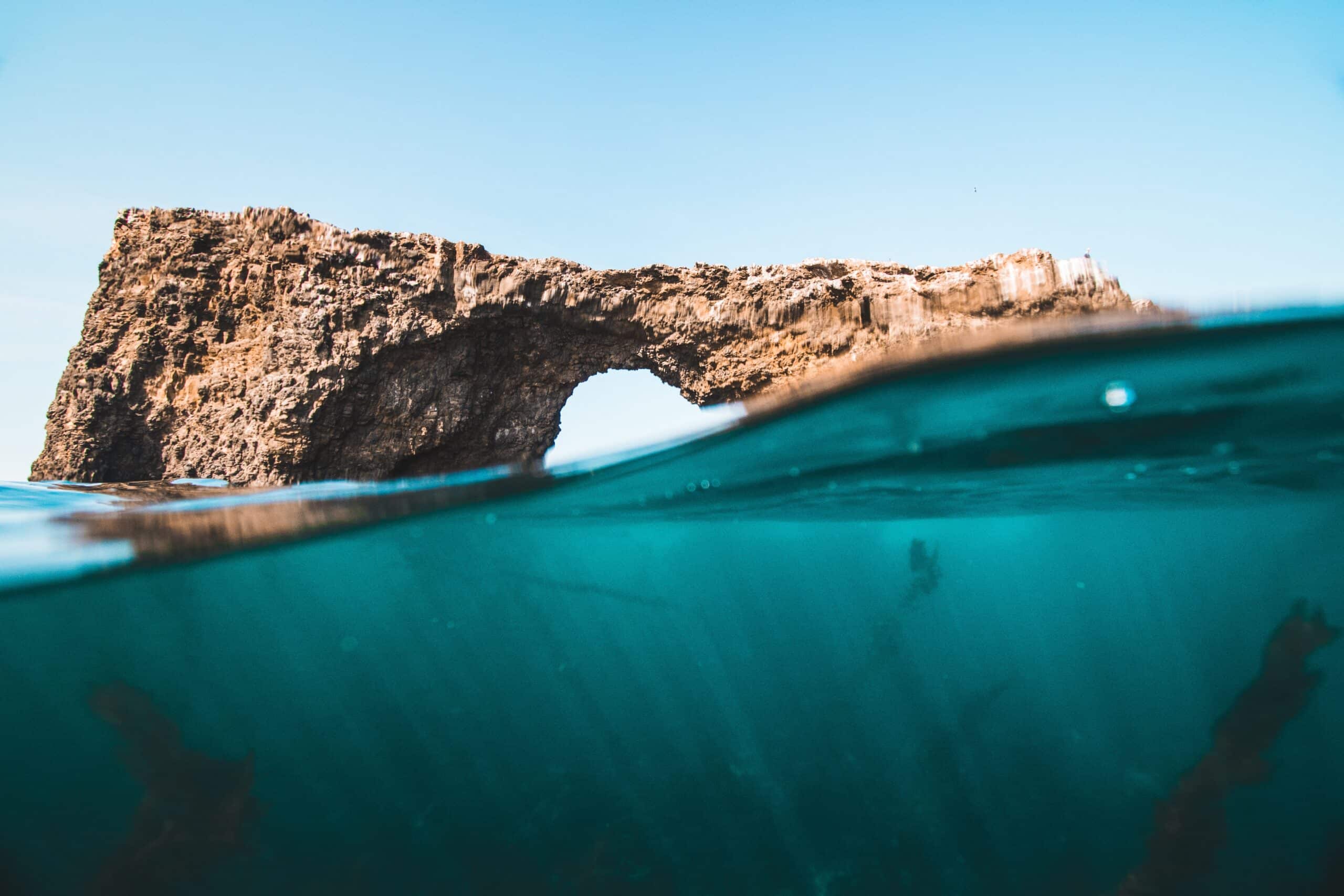 An underwater view of a rock arch in the ocean.