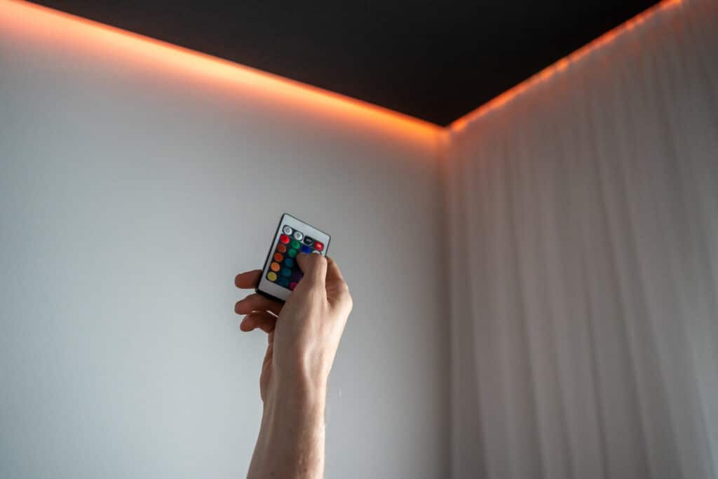 A person holding up a cell phone in a room with colored lights.