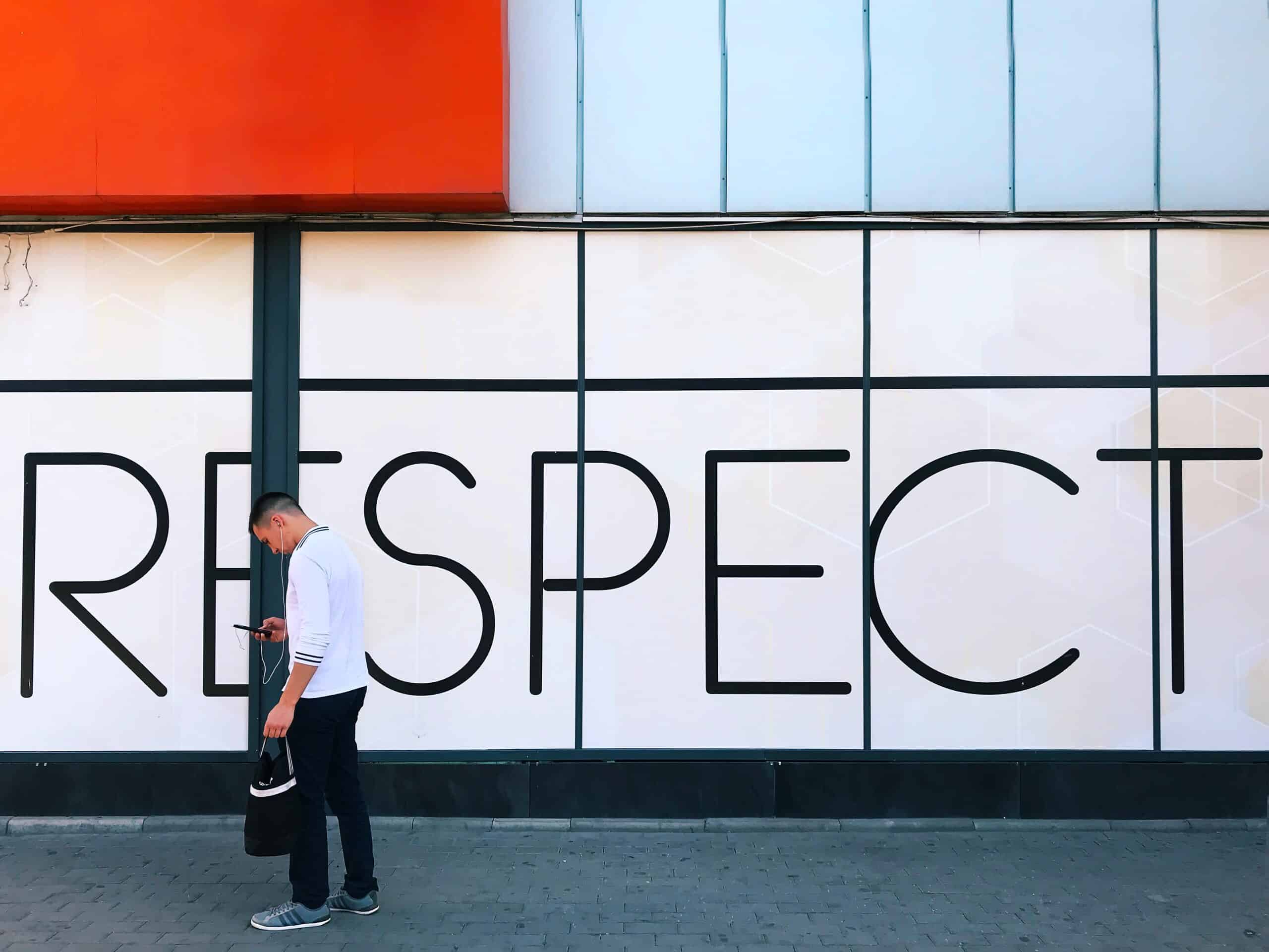 A man walking past a building that says respect.