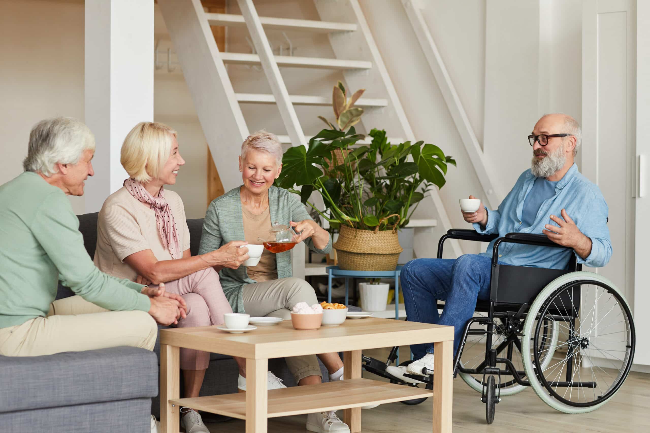 A group of elderly people sitting around a coffee table in a wheelchair.