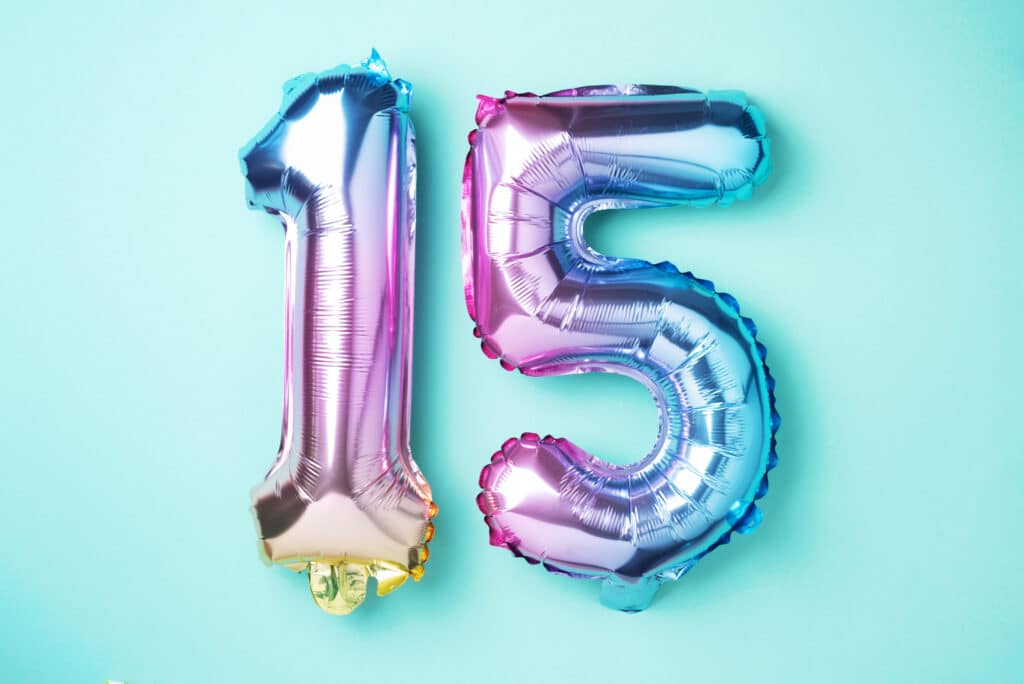 A group of foil balloons forming the number 15 on a blue background.