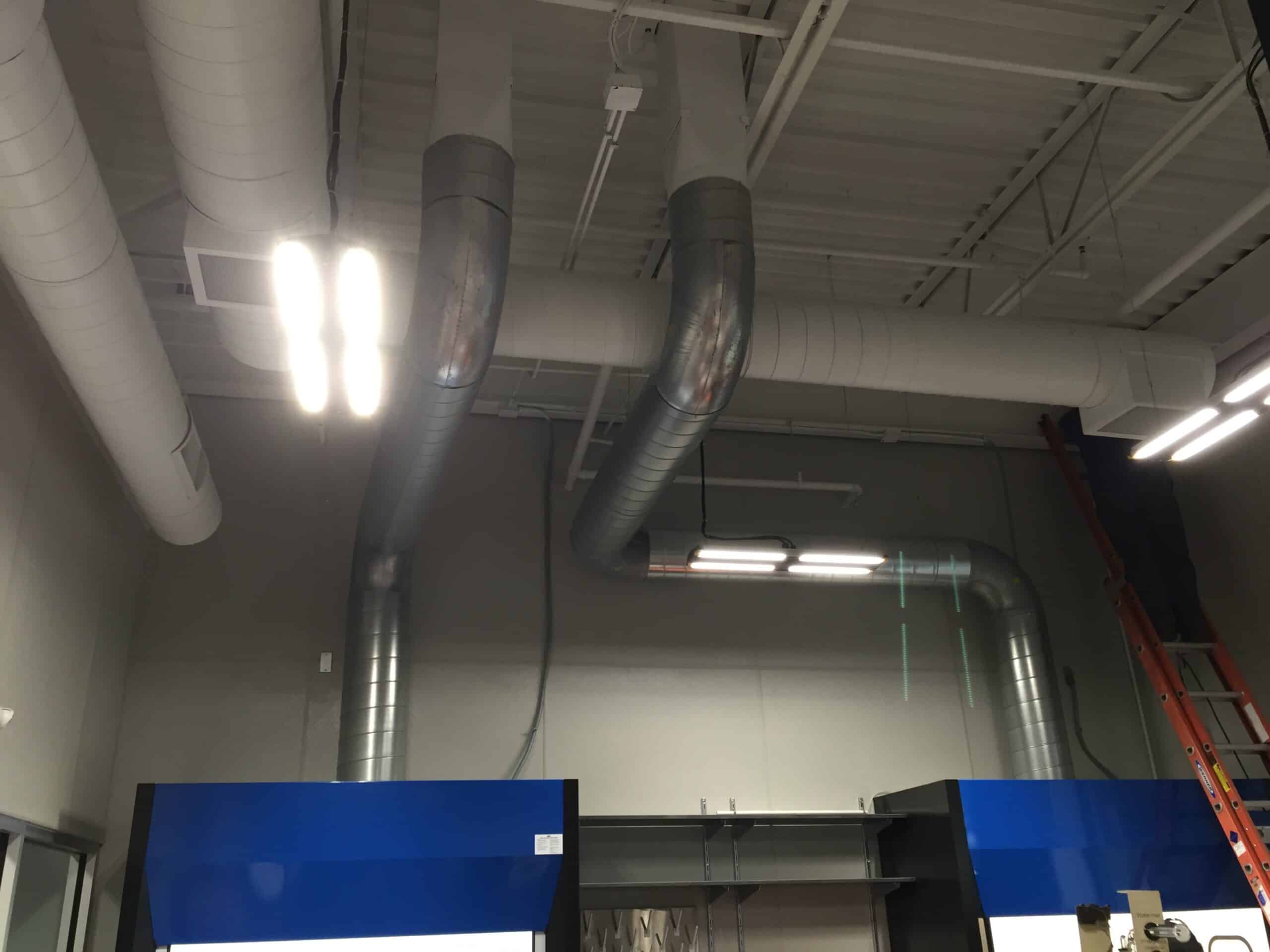 A room with ductwork and pipes in the ceiling.