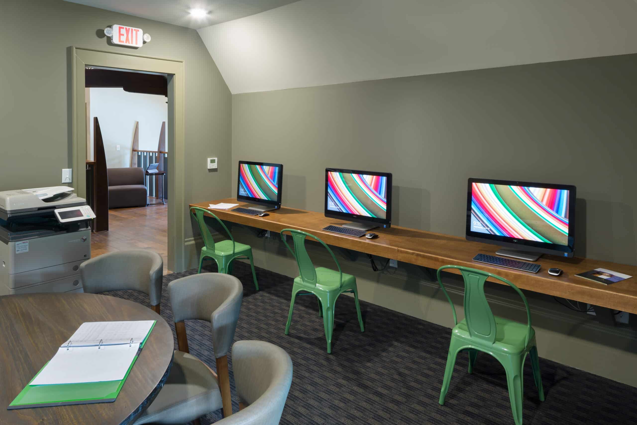 A computer desk with two monitors and a green chair.
