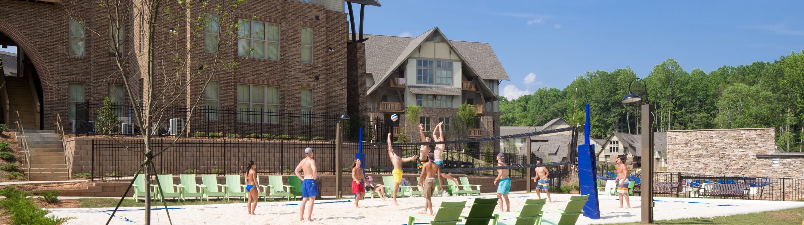 A group of people playing volleyball in front of a building.