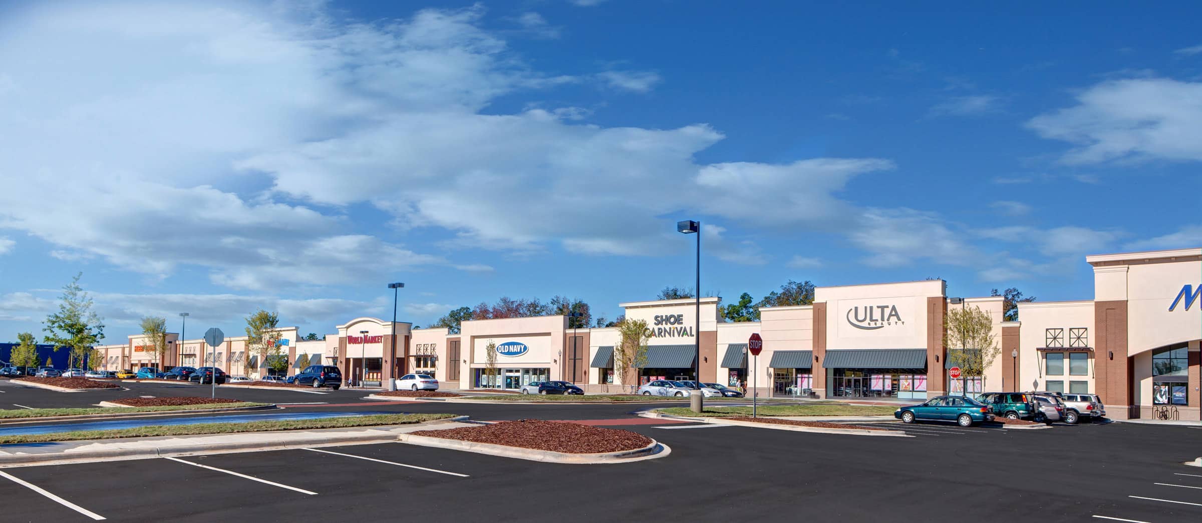 A rendering of a shopping center with cars parked in the parking lot.