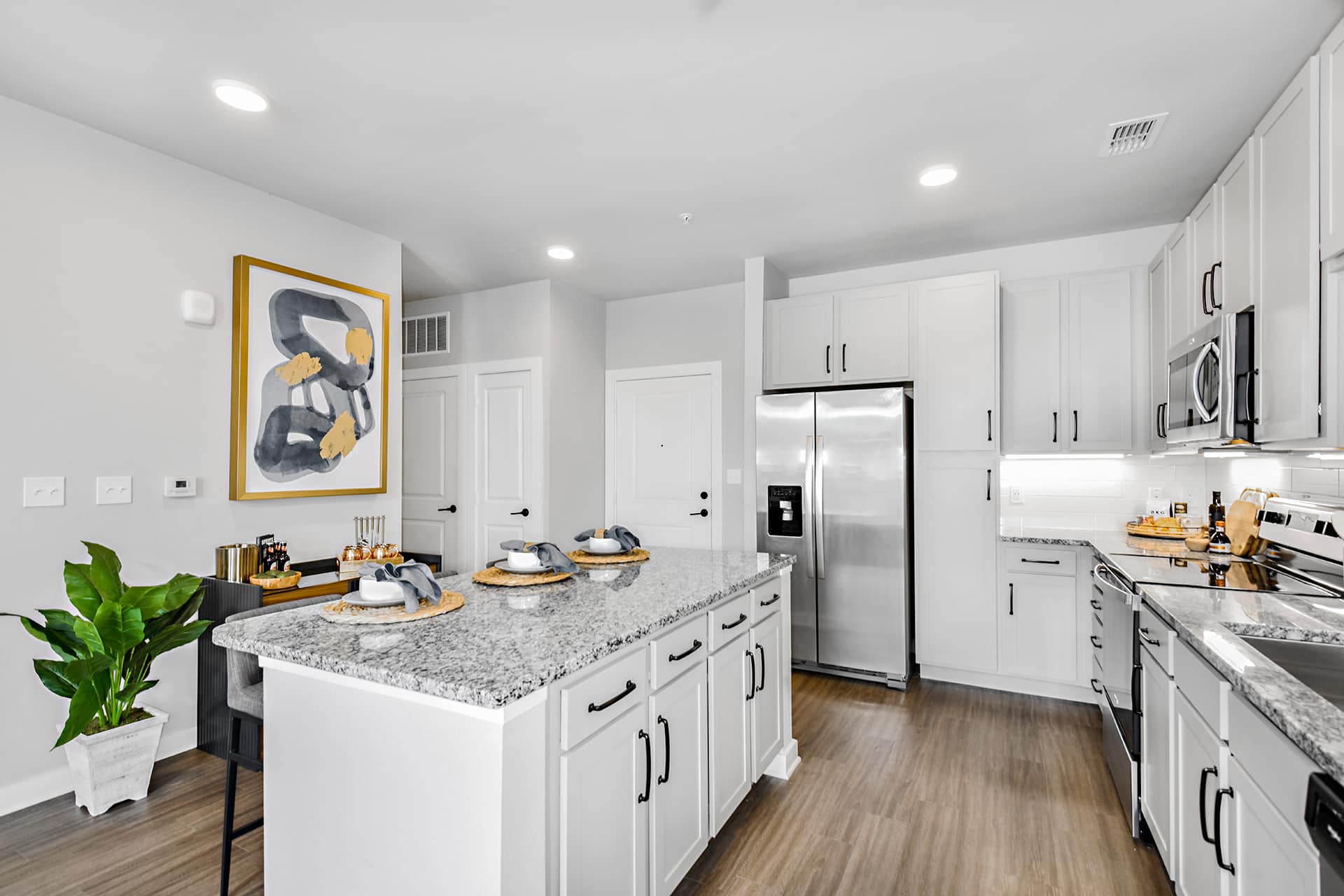 A kitchen with white cabinets, granite counter tops and stainless steel appliances.