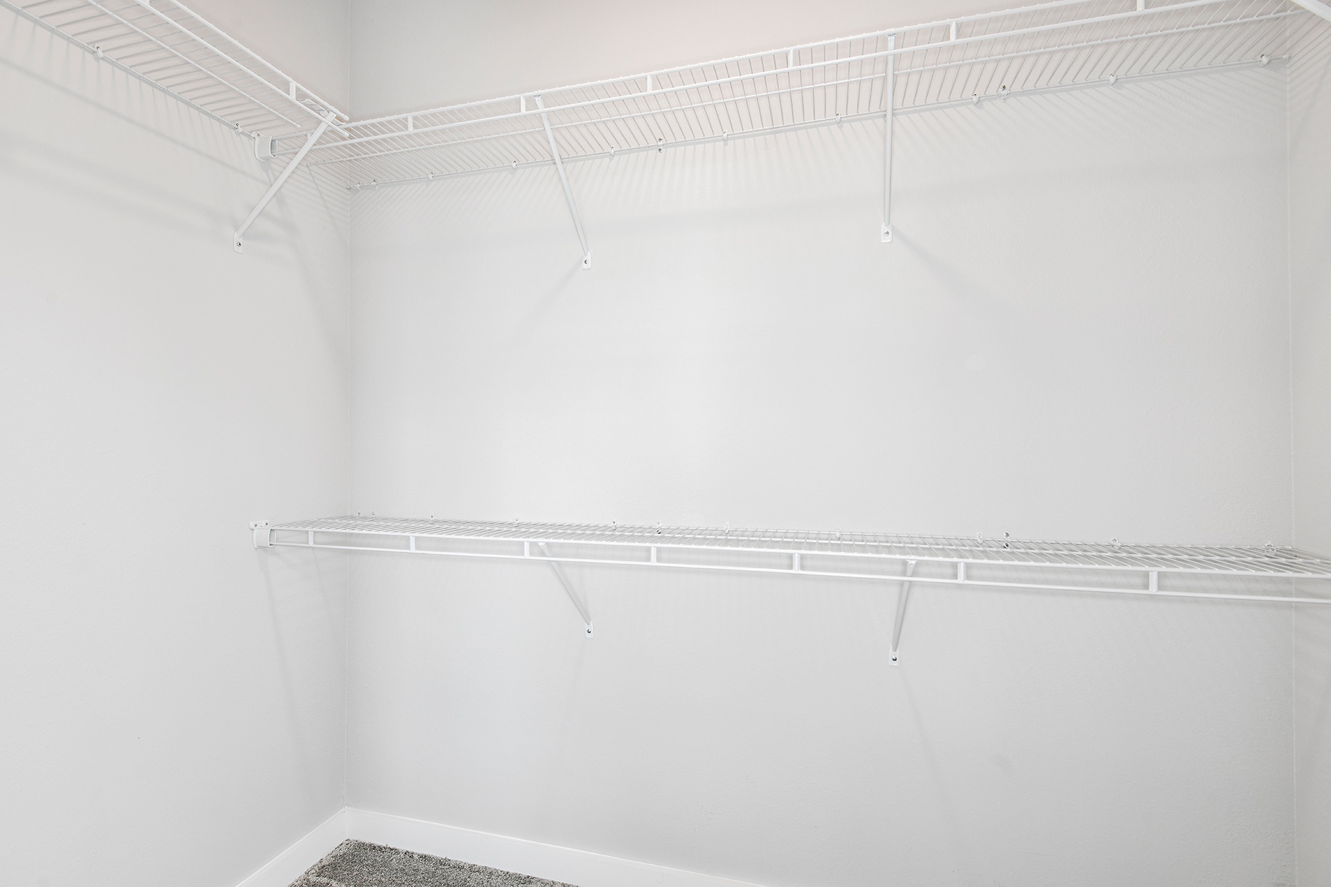 A white closet with shelves and a white floor.