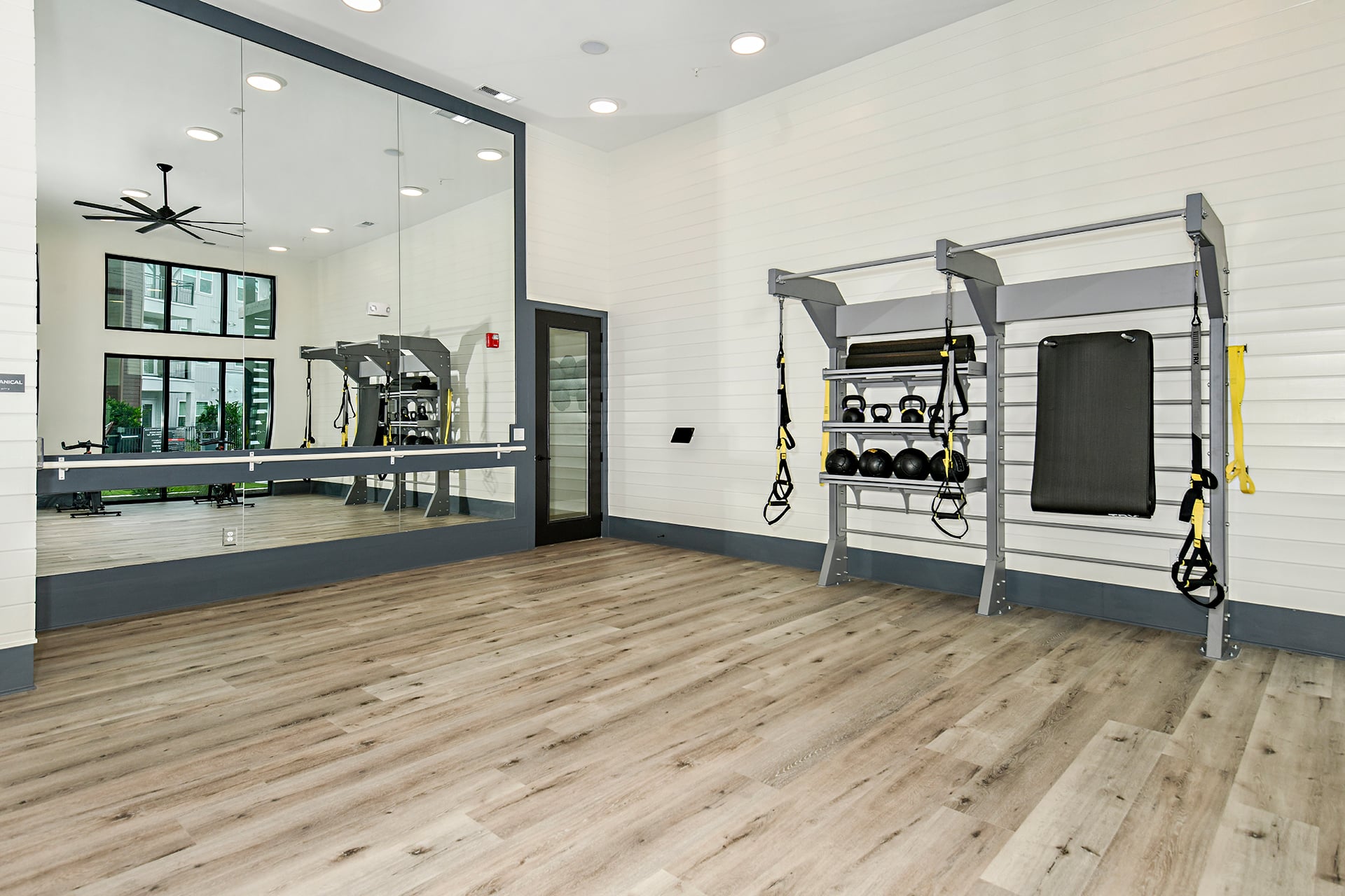 A gym room with mirrors and exercise equipment.