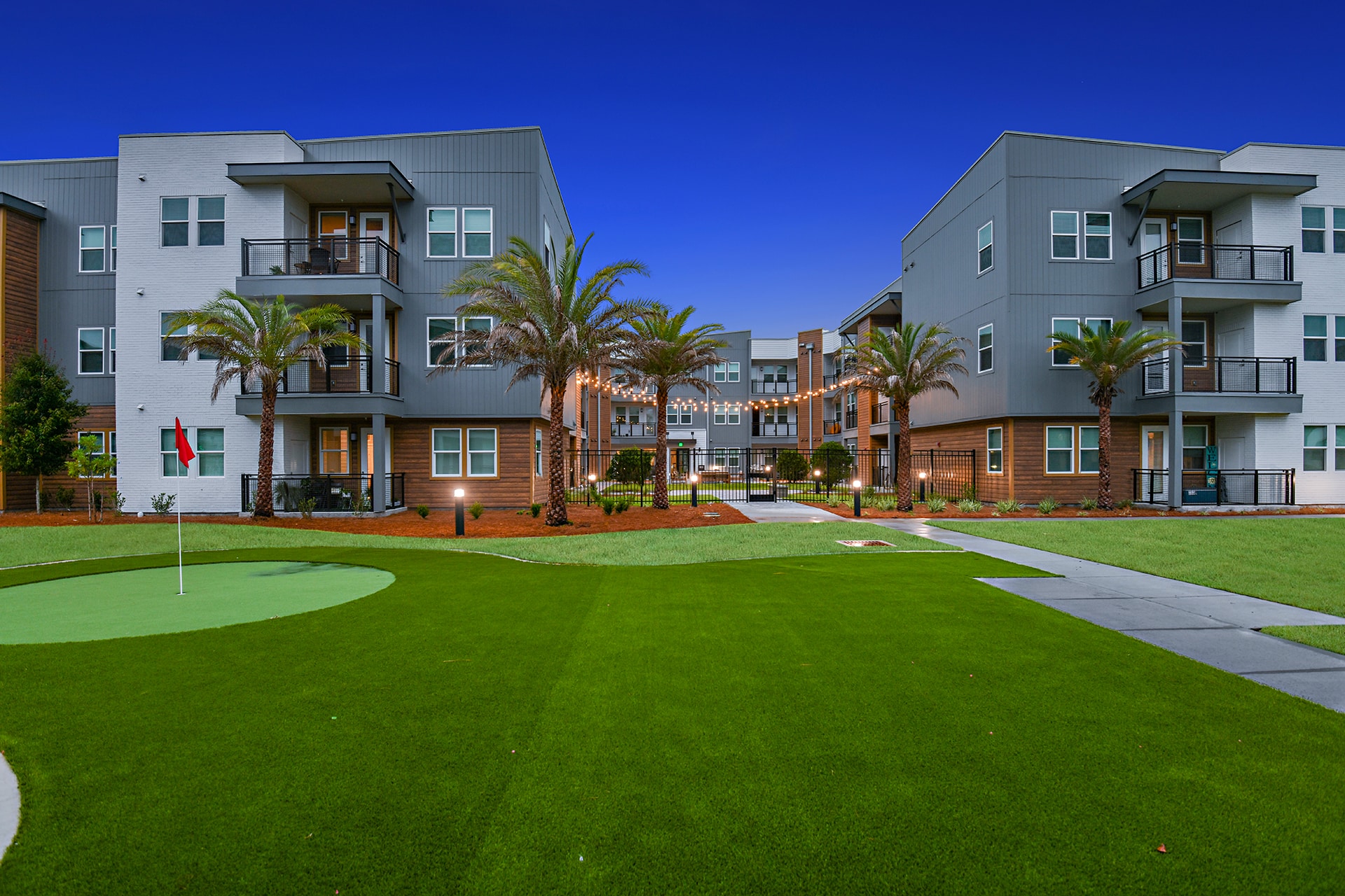 An apartment complex with a golf course in front of it.