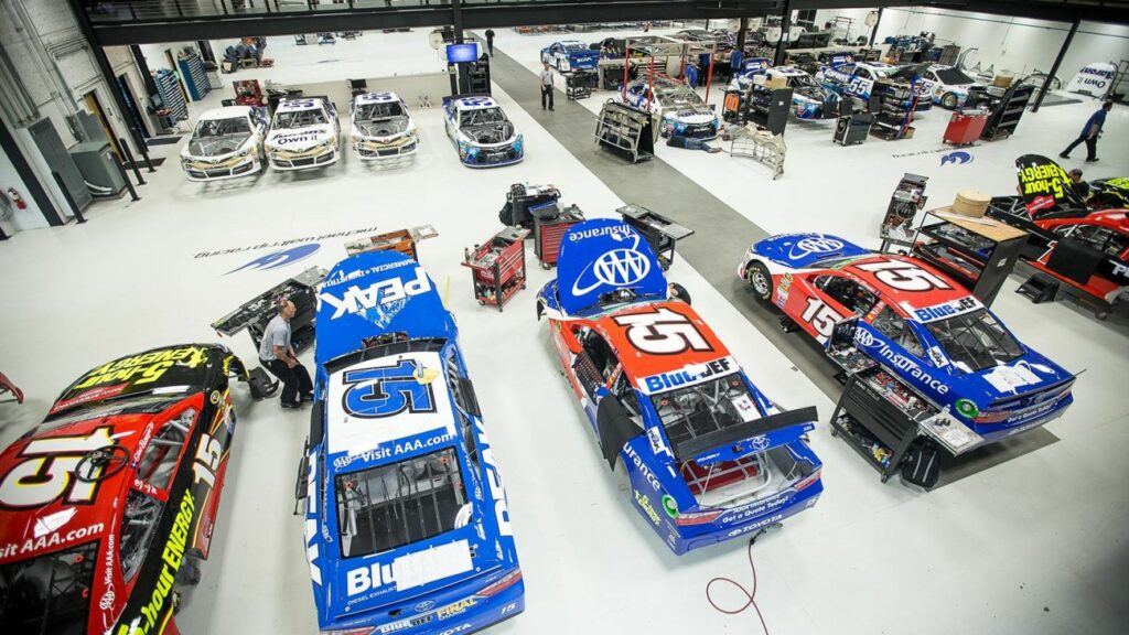 Several nascar cars are parked in a garage.