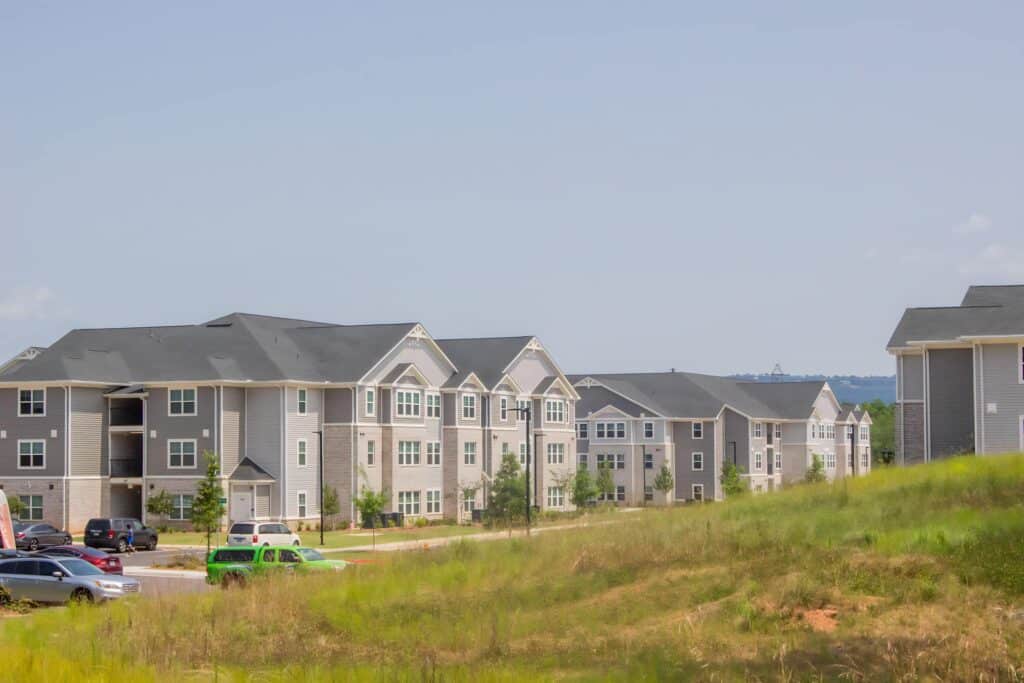 An apartment complex with cars parked on a grassy hill.