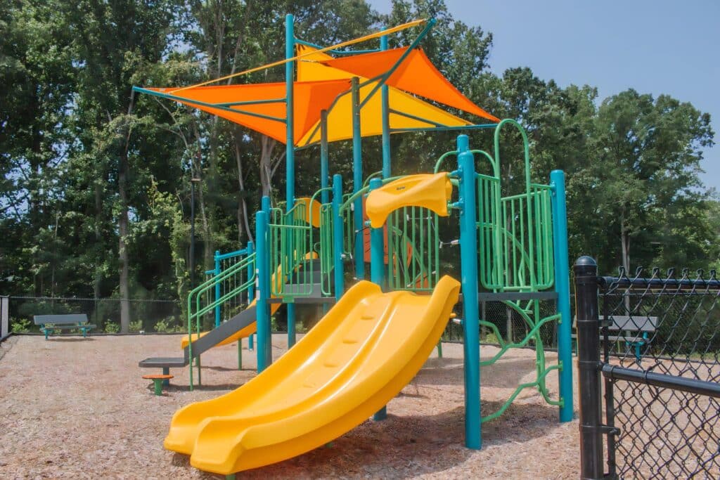 A playground with a yellow slide and yellow canopy.