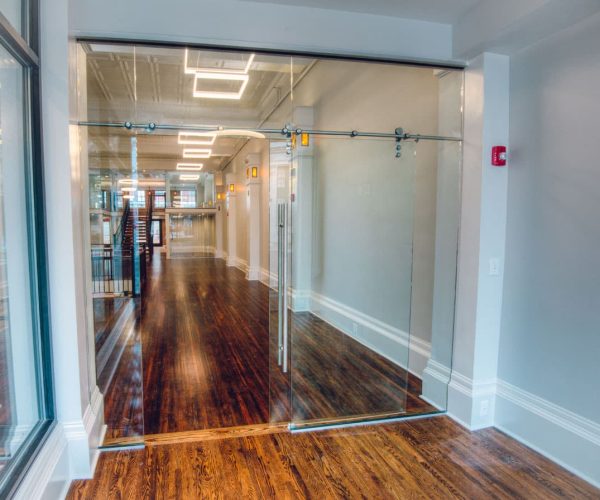 A hallway with glass doors and hardwood floors.